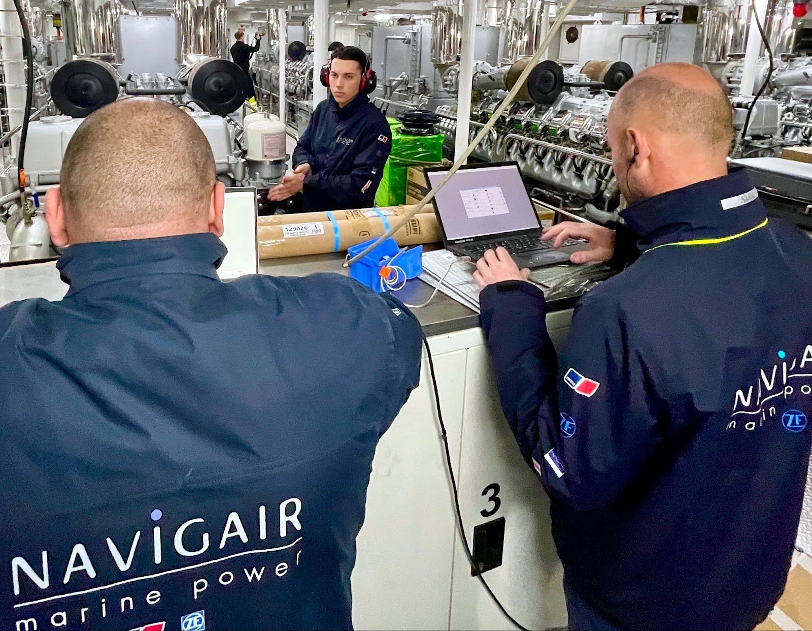 Navigair Team Performing a Survey Two Navigair employees working on engine maintenance, performing an engine survey on a superyacht.